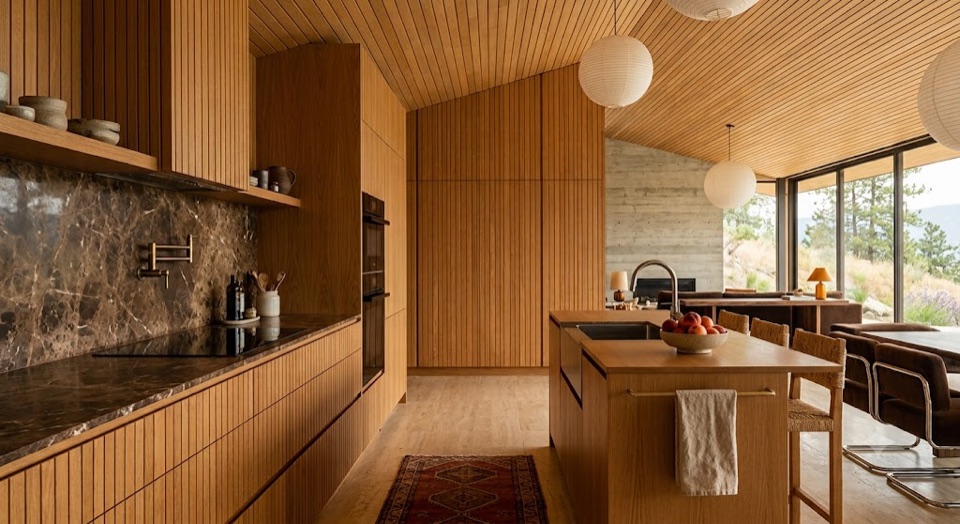 Warm oak, no visible hardware, brown marble to the ceiling. The island is the only object in the room.