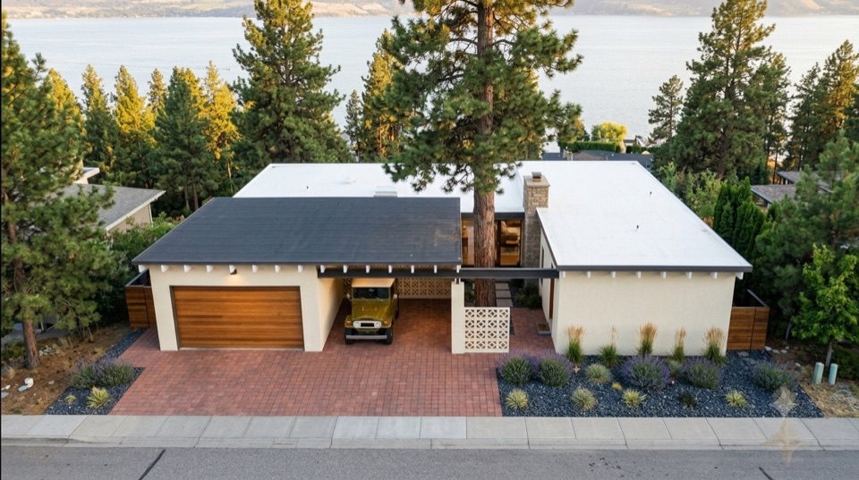 From above the street. One roof, a cedar garage door, breeze block, brick pavers, the lake behind.